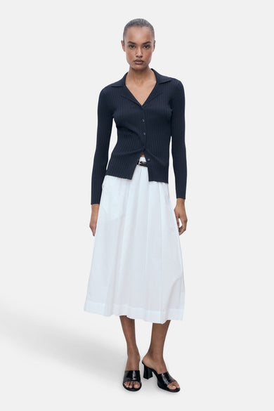 Blauwe cardigan van MANGO, gedragen met een witte uitlopende rok en zwarte muiltjes met hak.