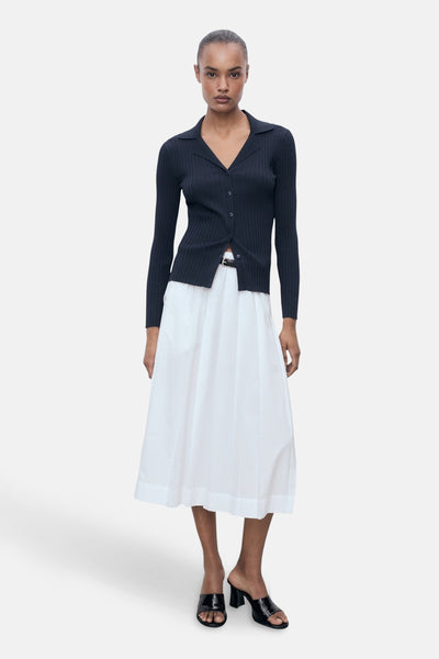 Blauwe cardigan van MANGO, gedragen met een witte uitlopende rok en zwarte muiltjes met hak.
