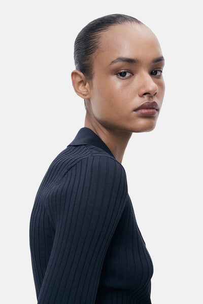 Blauwe MANGO-cardigan, van fijne ribgebreide stof, gedragen door een model met een donkere huidskleur.