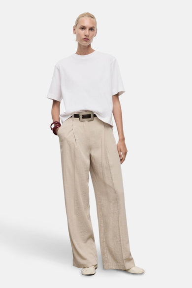 Wit T-shirt met korte mouwen van MANGO, gedragen met een beige broek met hoge taille en een bruine riem.