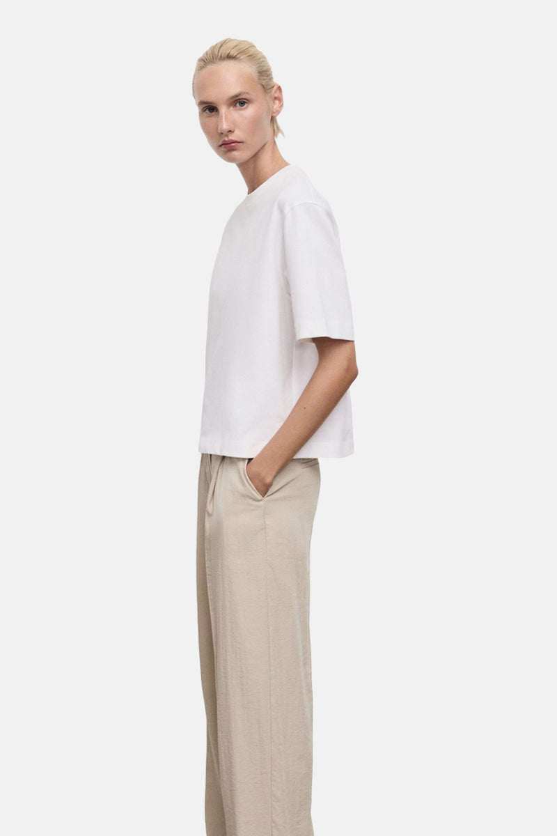 Wit T-shirt met korte mouwen van MANGO, gedragen met een beige broek met hoge taille.