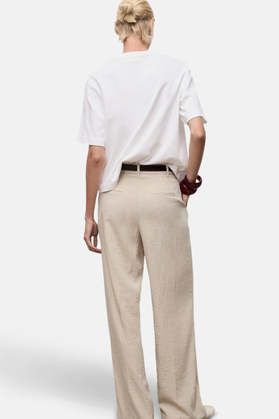 Wit T-shirt met korte mouwen van MANGO, gedragen met een beige broek en een bruine riem.