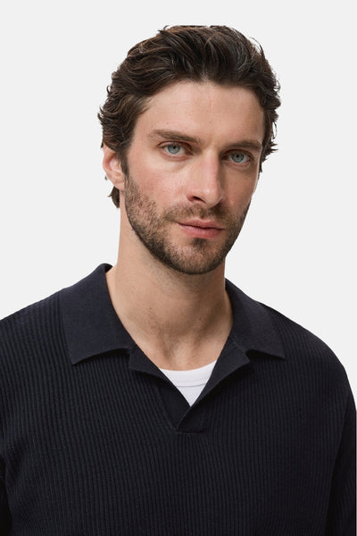 Pull à col rond bleu de MANGO, en tricot côtelé, porté sur un t-shirt blanc.
