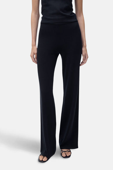 Pantalon bleu marine par MANGO, coupe évasée, en maille fine, porté avec un haut noir uni et des sandales.