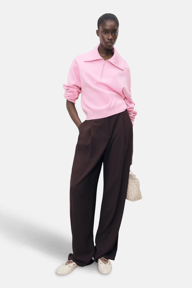 Roze coltrui van MANGO, gedragen met een bruine broek en crèmekleurige lage schoenen.