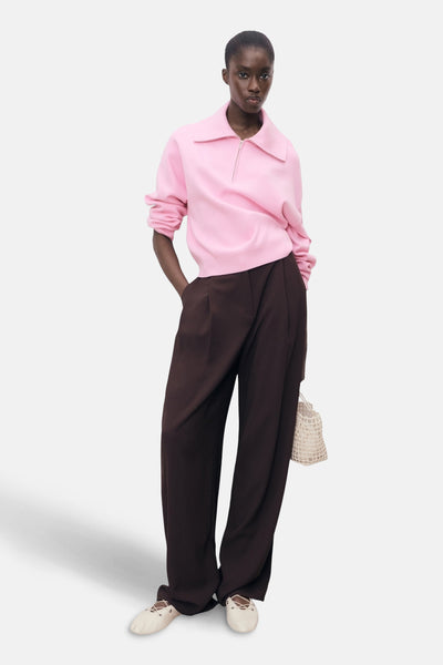 Roze coltrui van MANGO, gedragen met een bruine broek en crèmekleurige lage schoenen.