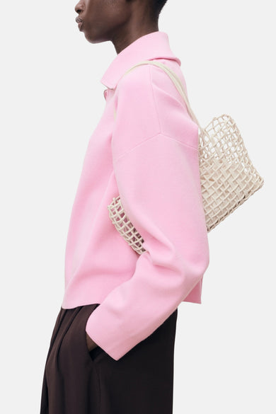 Roze coltrui van MANGO, gedragen met een bruine broek en een beige nettas, zijwaartse weergave.