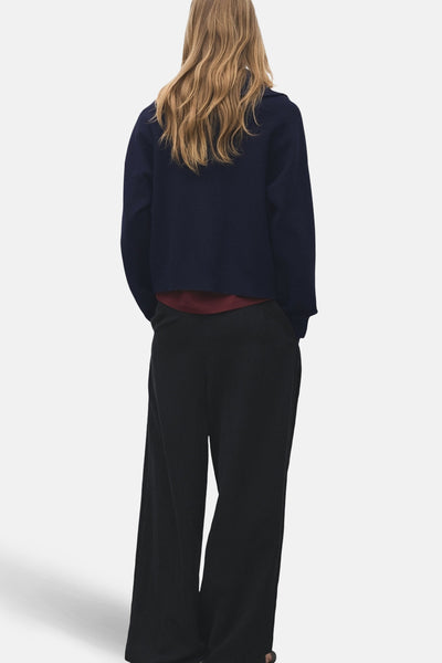Blauwe coltrui van MANGO, gedragen met een wijde zwarte broek en een bordeauxrood T-shirt, achtergezicht.