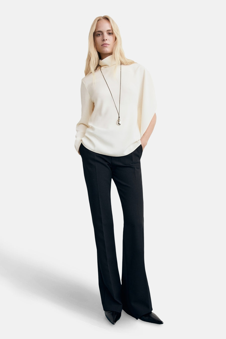 Wit overhemd met lange mouwen van MANGO, gedragen met een zwarte broek en een lange ketting.