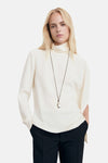 Witte blouse met lange mouwen van MANGO, gedragen met een zwarte broek en een hangerketting.