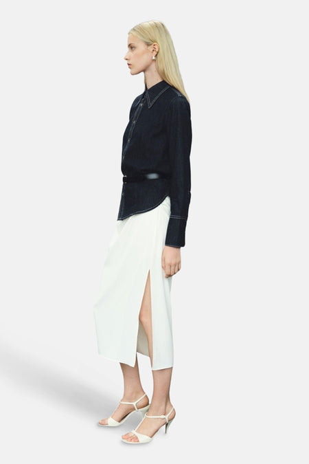 Donkerblauwe spijkerblouse met lange mouwen van MANGO, gedragen met een zwarte riem en een witte rok met split.