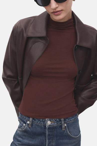 T-shirt à manches longues brun de MANGO, porté avec une veste en cuir marron et un jean bleu.