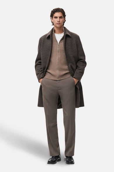 Gilet brun de MANGO, porté sur un t-shirt blanc, avec pantalon marron et manteau à carreaux.