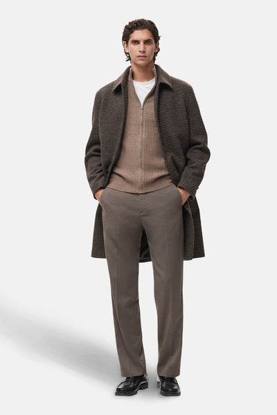 Gilet brun de MANGO, porté sur un t-shirt blanc, avec pantalon marron et manteau à carreaux.