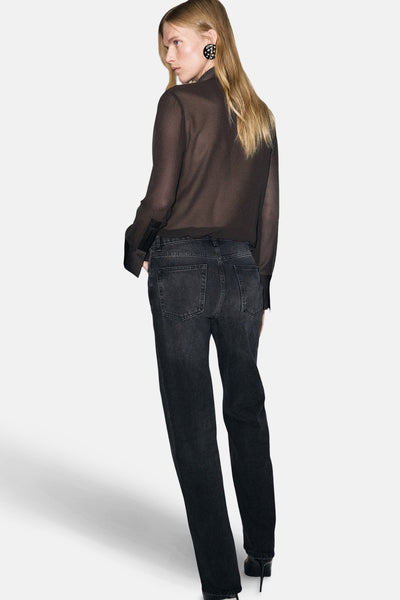Chemise à manches longues marron de MANGO, en tissu transparent porté avec un jean noir et des chaussures à talons noirs.
