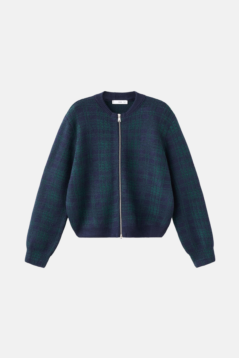 Multikleurend gilet van MANGO, gedragen met een donkere jeans, een suède tas en een ronde zonnebril.