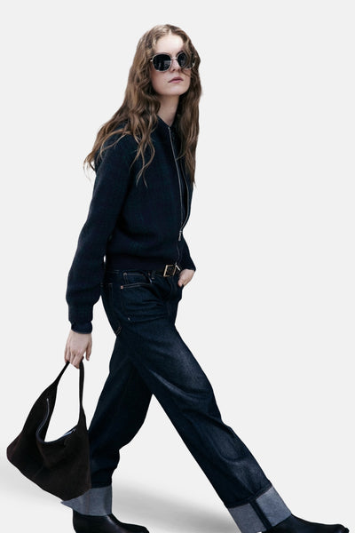 Gilet multicolore de MANGO, porté avec un jean foncé, un sac en daim et des lunettes de soleil rondes.