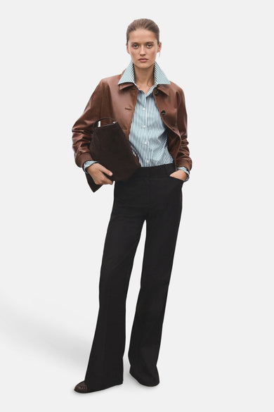 Chemise à manches longues verte à rayures, de MANGO, portée avec une veste en cuir et un pantalon noir.