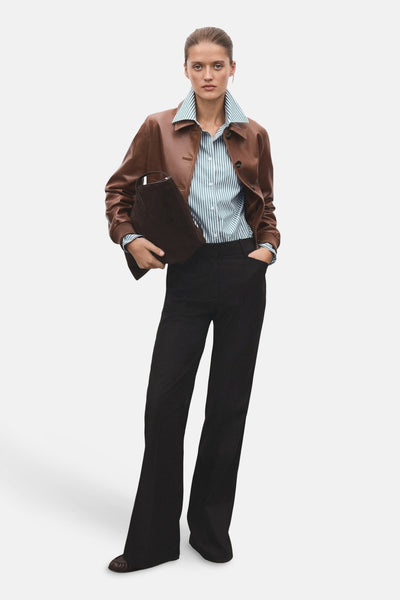 Chemise à manches longues verte à rayures, de MANGO, portée avec une veste en cuir et un pantalon noir.