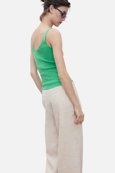 Débardeur vert en maille de MANGO, porté avec un pantalon taille haute ample couleur crème.