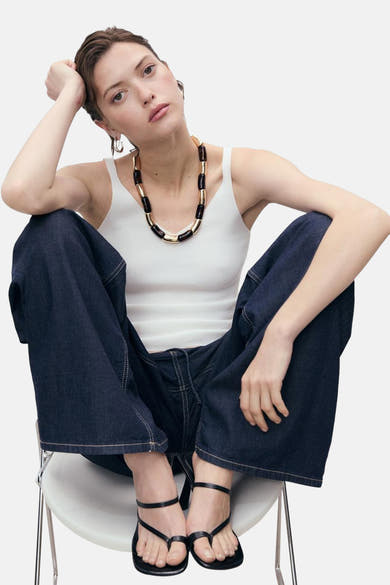 Witte tanktop van MANGO, gedragen met een wijde donkerblauwe jeans en zwarte sandalen met bandjes.