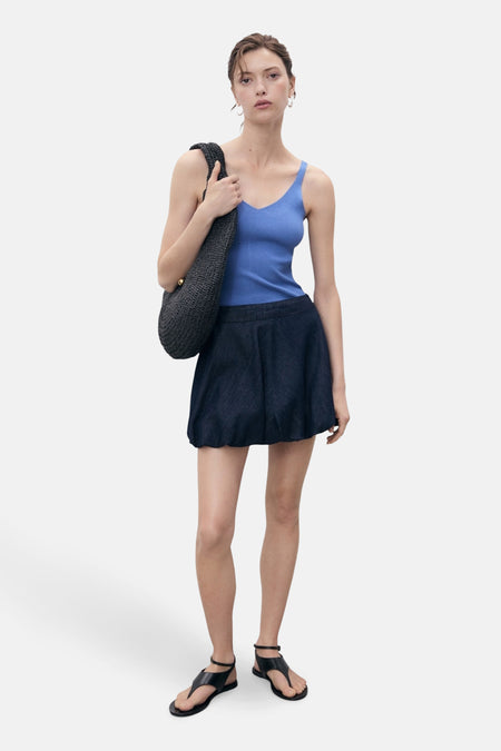 Blauwe tanktop van MANGO, gedragen met een wijde korte rok en zwarte sandalen.