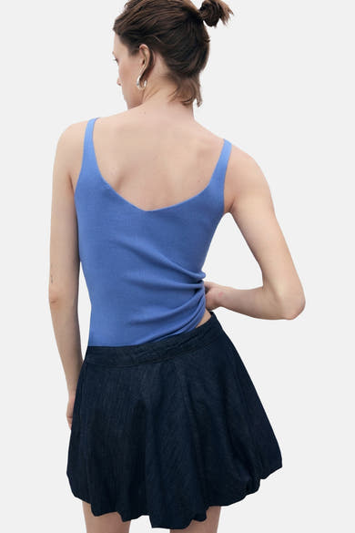 Blauwe MANGO tanktop, met dunne bandjes, gedragen met een donkerblauwe, korte pofrok, van achteren gezien.