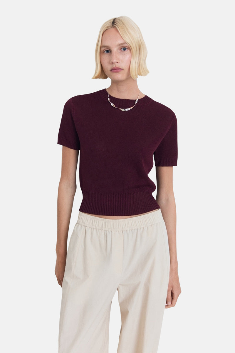 Bordeaux ronde hals trui van MANGO, gedragen met een beige high-waist broek en een zilveren ketting.