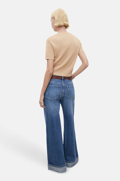 Beige ronde hals trui van MANGO, gedragen met een blauwe flared jeans en een bruine riem, achterzijde.