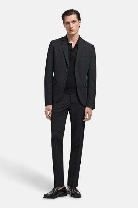 Pantalon de costume noir de MANGO, porté avec une veste de costume et des mocassins en cuir.