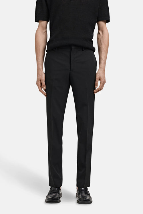 Pantalon de costume noir de MANGO, porté avec un t-shirt noir et des mocassins en cuir noir.