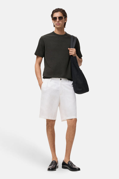 Zwart T-shirt met korte mouwen van MANGO, gedragen met een witte korte broek, loafers en een draagtas.