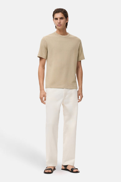 Beige T-shirt met korte mouwen van MANGO, gedragen met een witte broek en zwarte sandalen.