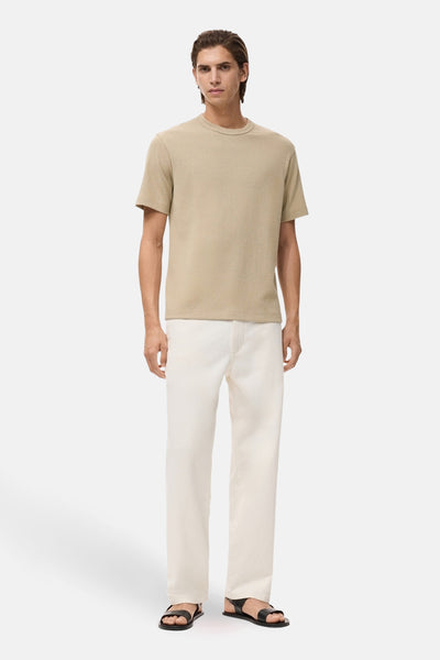 Beige T-shirt met korte mouwen van MANGO, gedragen met een witte broek en zwarte sandalen.