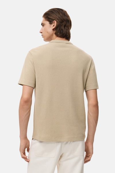 Beige T-shirt met korte mouwen van MANGO, crêpe textuur, gedragen met een witte broek, achtergezicht.