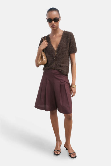 Bruine cardigan met textuurlook van MANGO gedragen met geplooide shorts en een handtas.