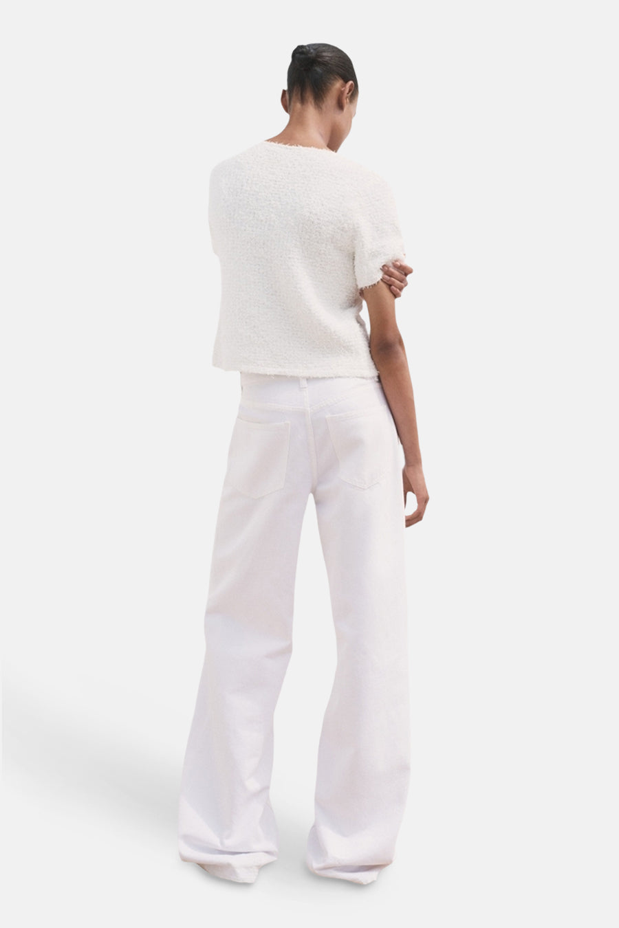 Cardigan blanc de MANGO, porté avec un pantalon large blanc, vue de dos.
