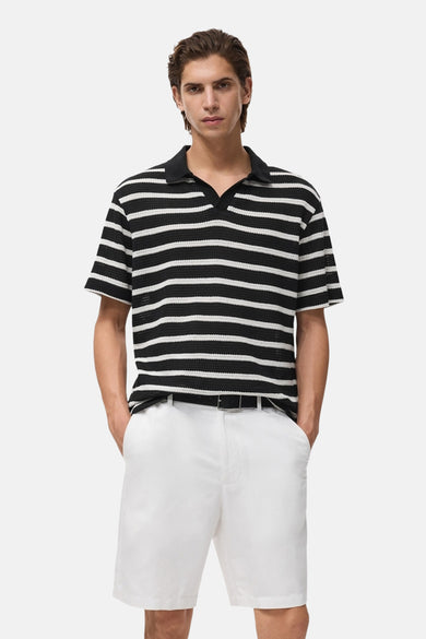 Zwart poloshirt met korte mouwen van MANGO, witte horizontale strepen, gedragen met een witte korte broek.