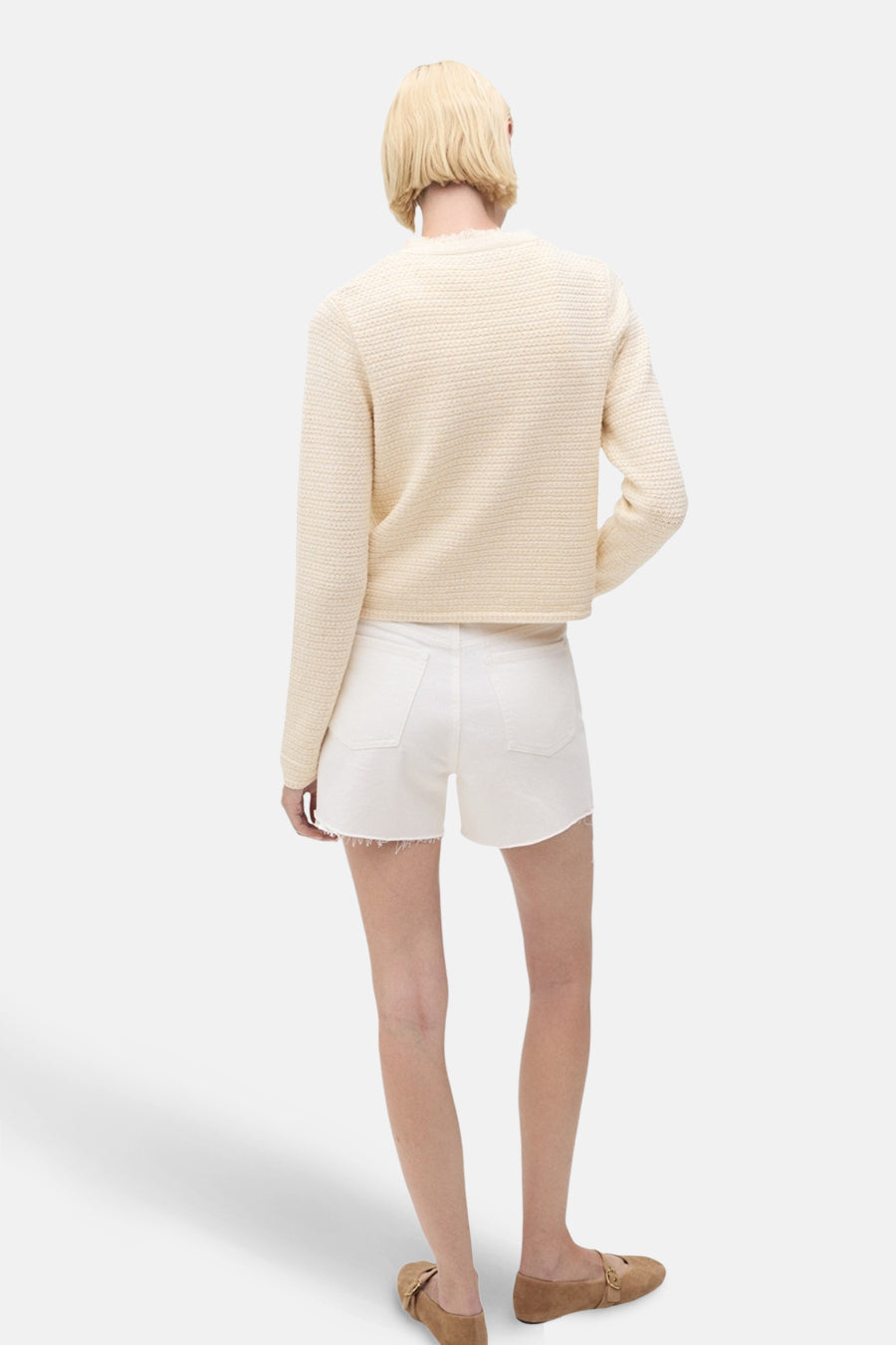 Ecru vest van MANGO, gebreide textuur, gedragen met een witte korte broek en bruine platte schoenen, achterzicht.