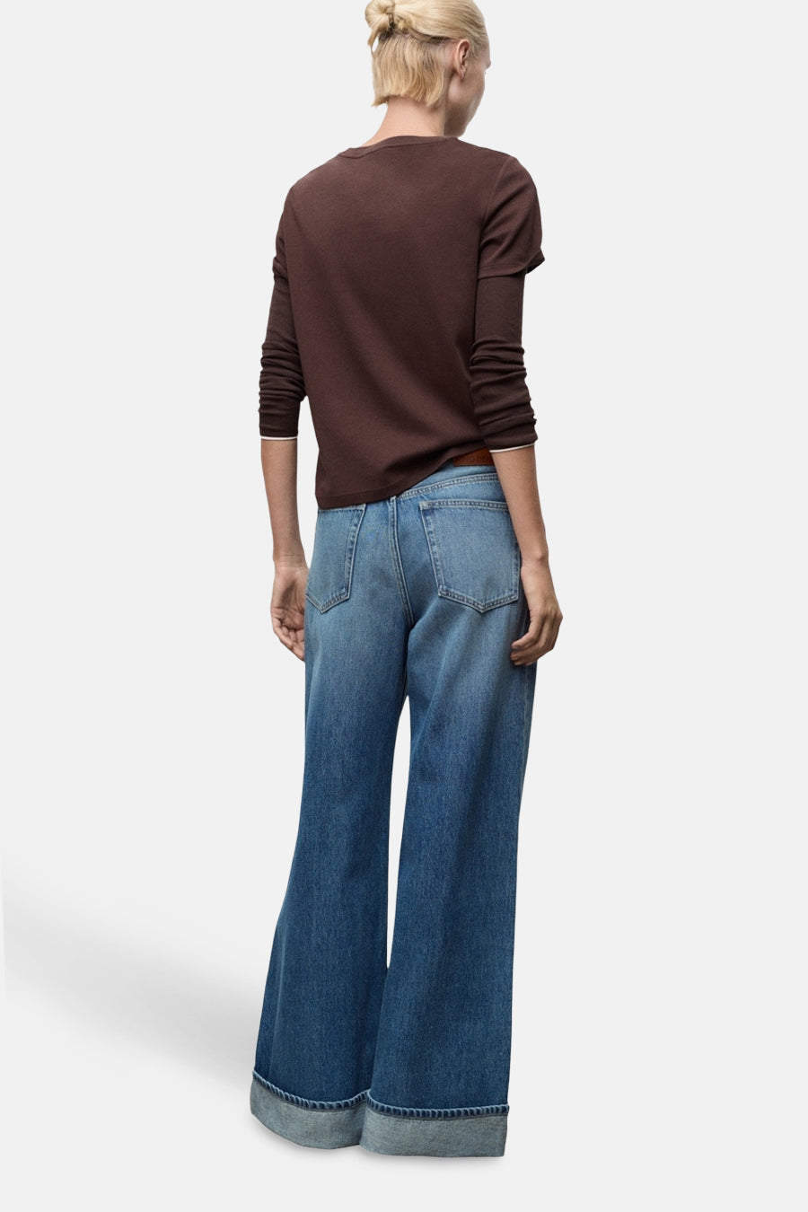 Jean large bleu moyen de MANGO, avec ourlet retroussé, porté avec un t-shirt marron à manches longues.
