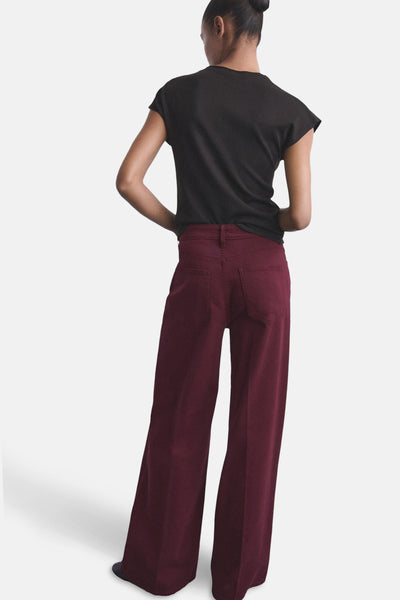 Jean coloré bordeaux de MANGO, coupe ample, avec poches arrière et porté avec un t-shirt noir.