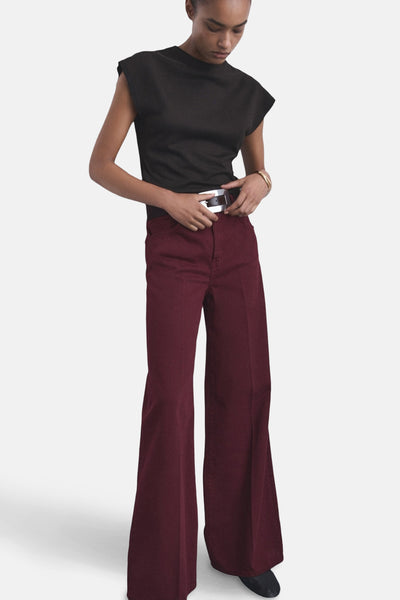 Bordeauxgekleurde jeans van MANGO, losse pasvorm, met een zilveren riem en een zwart mouwloos T-shirt.
