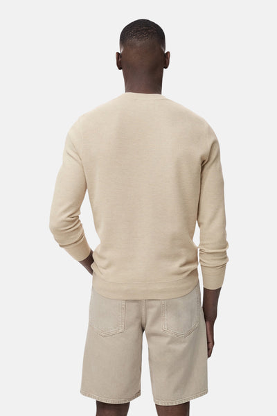 Pull à col rond beige de MANGO, porté avec un short beige, vue de dos.