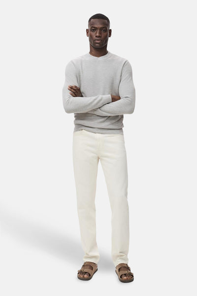 Grijze trui met ronde hals van MANGO, gedragen met gebroken witte jeans en bruine sandalen met twee bandjes.