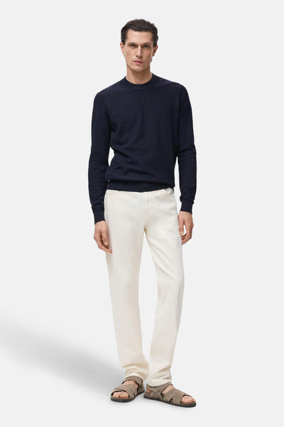 Blauwe trui met ronde hals van MANGO, gedragen met een witte broek en gekruiste sandalen.