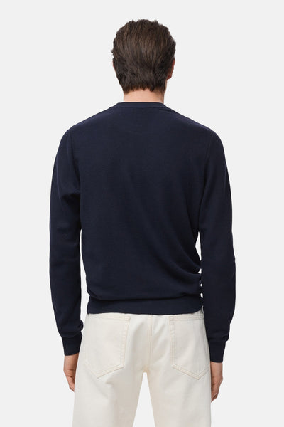 Blauwe trui met ronde hals van MANGO, van achteren gezien, gedragen met een gebroken witte broek.
