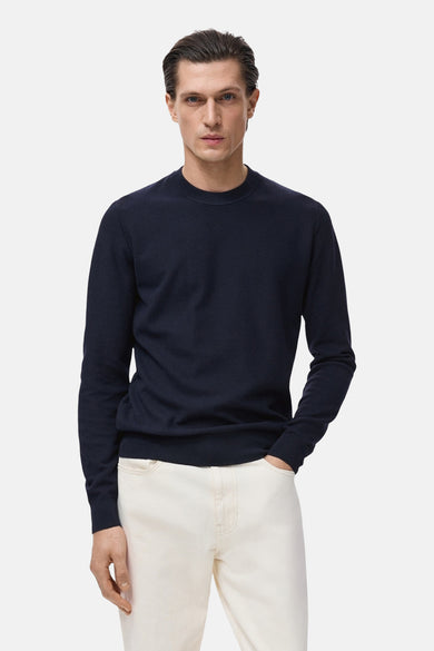 Blauwe trui met ronde hals van MANGO, gedragen met een witte broek en met een fijne textuur.