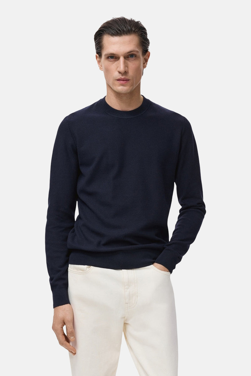 Blauwe trui met ronde hals van MANGO, gedragen met een witte broek en met een fijne textuur.