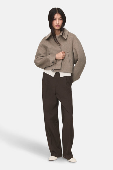 Korte beige jas van MANGO met een reverskraag, gedragen over een witte trui en een wijde bruine broek.