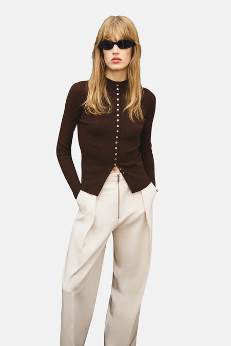 Bruin gilet van MANGO gedragen met een broek met hoge taille en zichtbare rits en een zonnebril.